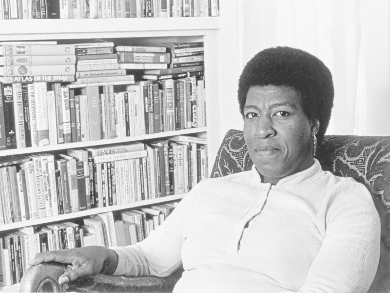 Octavia Butler next to a bookshelf packed with books. Courtesy WBEZ.