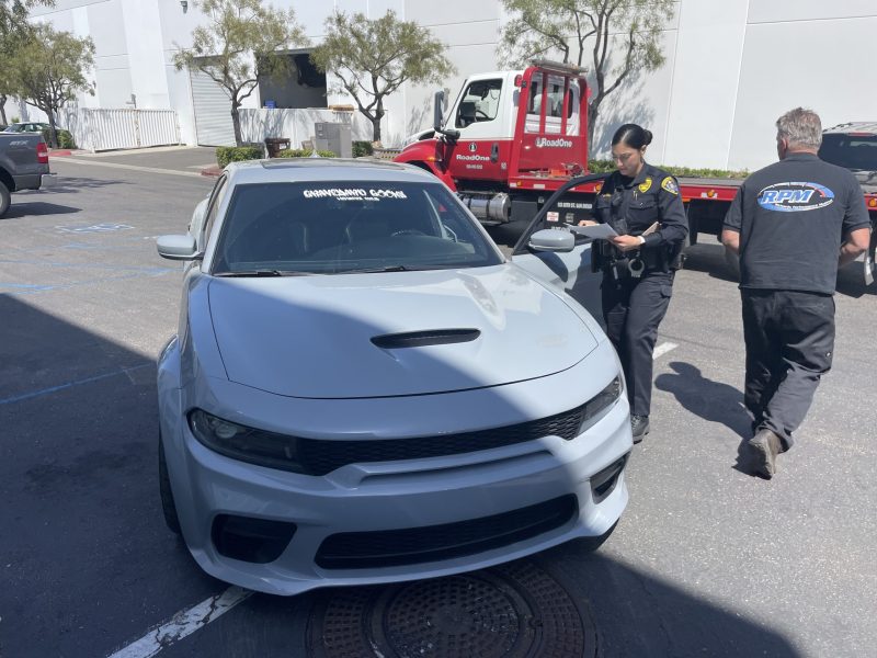 A police officer next to a car that was impounded from a "sideshow takeover" event. Courtesy SDPD