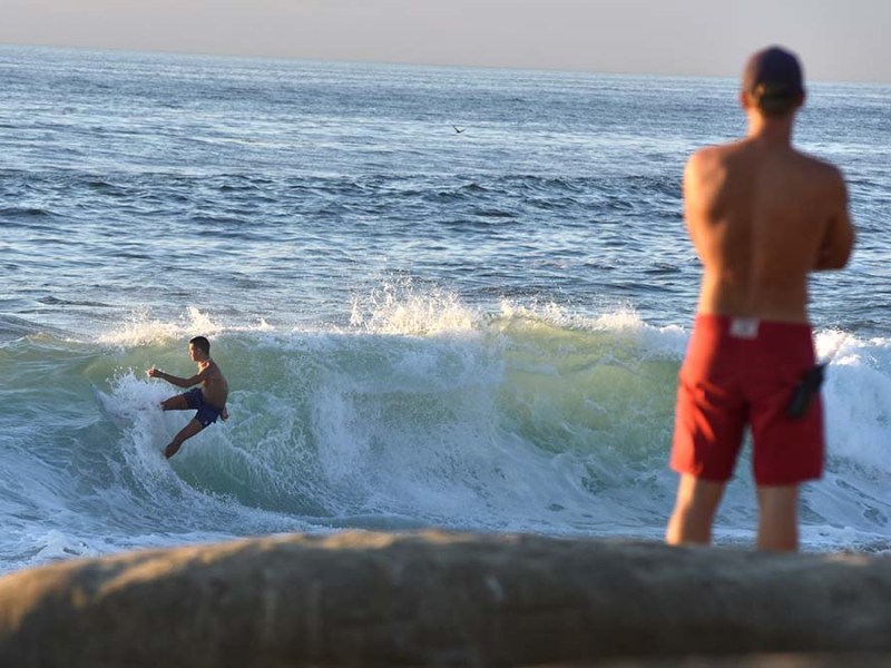 San Diego lifeguard watches surfer at La Jolla's Windandsea Beach during a high tide.