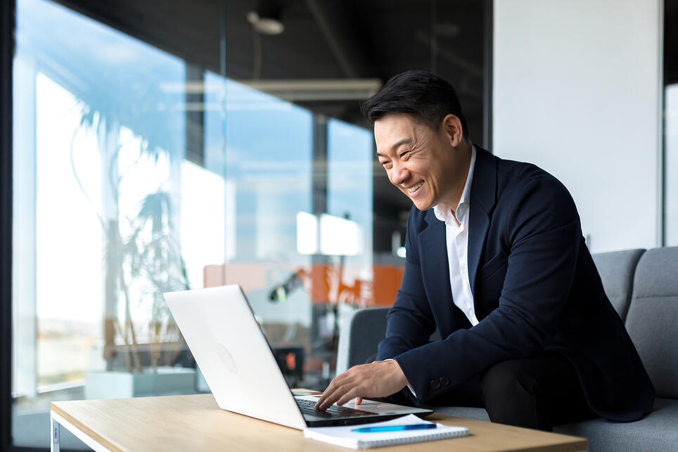 Business-man-smiling-and-proud-looking-at-laptop-how-to-end-an-email