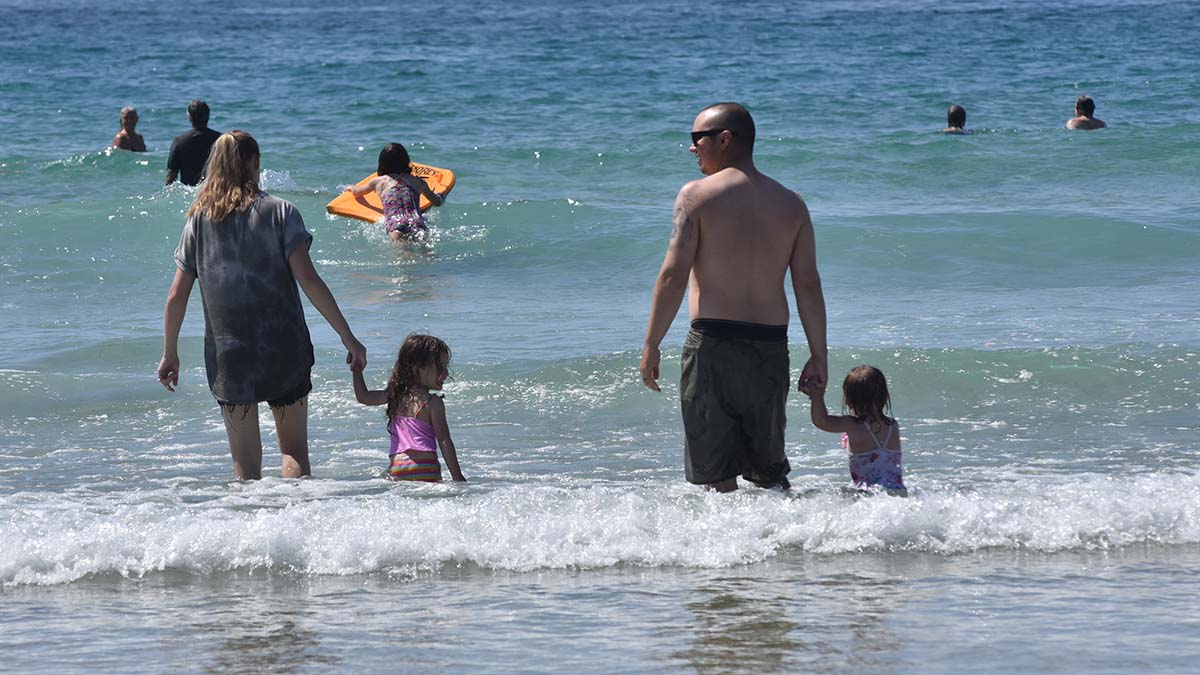 Families take refuge in cool ocean waves at La Jolla Shores to escape high temperatures. Photo by Chris Stone