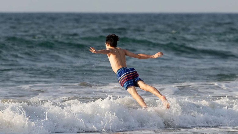 A boy plunges into the ocean at La Jolla Shores. Photo by Chris Stone