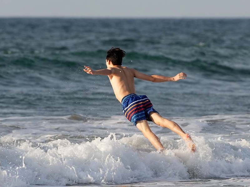A boy plunges into the ocean at La Jolla Shores. Photo by Chris Stone