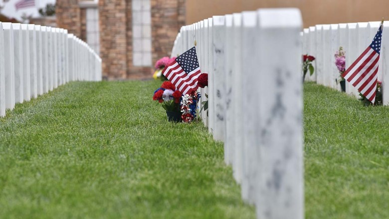 Families add flags to headstones at Miramar National Cemetery. Photo by Chris Stone