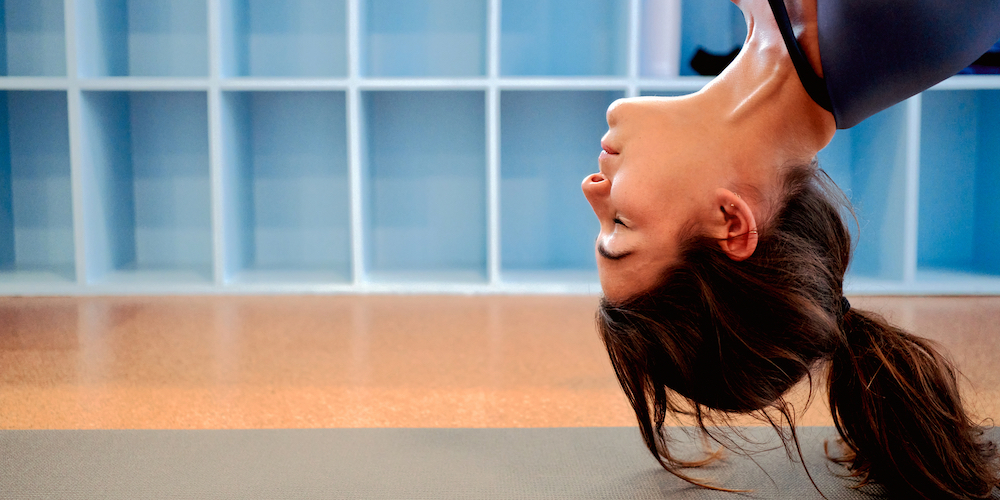 A woman smiling as she meditates upside-down