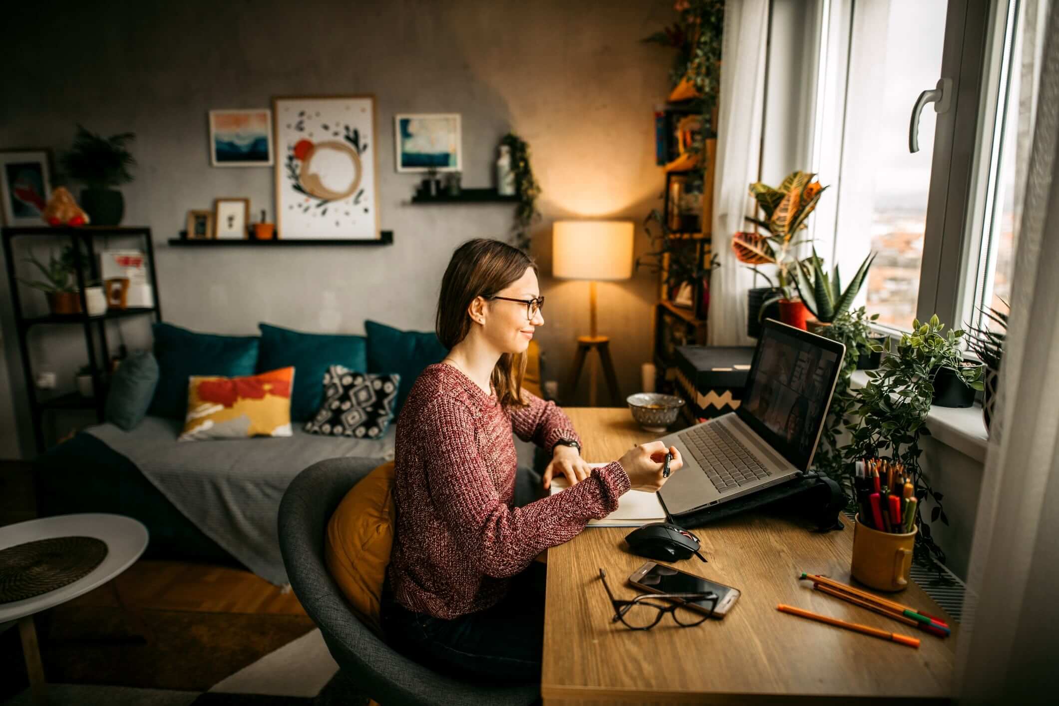 smiling woman sitting at desk with laptop