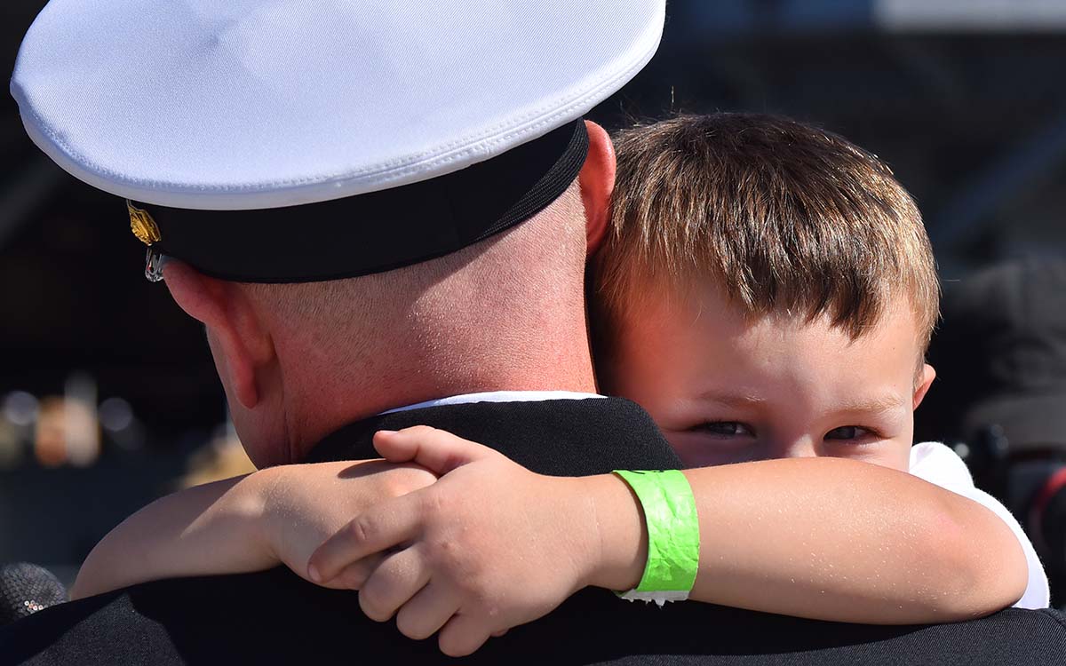 Julian Blodgett, 4, hangs on tight to his father after his return to San Diego. Photo by Chris Stone